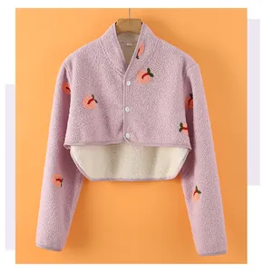 Detail view of pink fleece shoulder warmer with peach embroidery and soft white lining