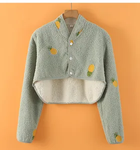 Close-up of light green fleece shoulder warmer with yellow pineapple prints and white buttons