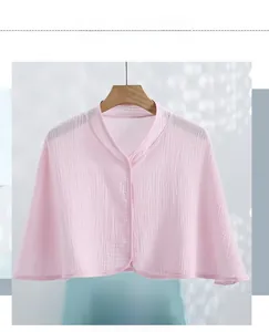 Close-up of light pink cotton gauze nursing shawl with buttons and textured fabric finish