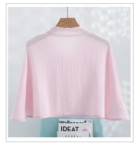 Close-up of pink cotton gauze nursing shawl with textured fabric on a wooden hanger
