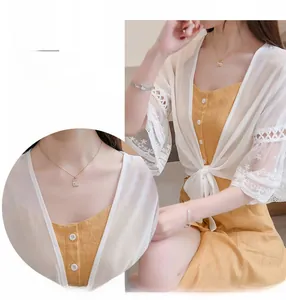 Détail du décolleté d'un cardigan en dentelle blanche avec broderie et cordon de serrage