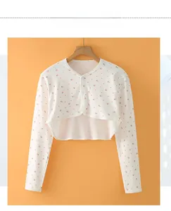Close-up of white cotton baby shoulder shrug with pink strawberry pattern and buttons
