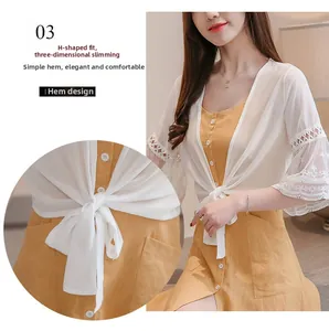 Détail de robe en coton jaune avec lien à la taille et cardigan pare-soleil en dentelle blanche