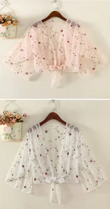 Detail of floral embroidery on sheer mesh sun protection shrug with delicate lace ties