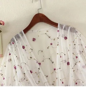 Detailed embroidery of purple floral motifs on a sheer white mesh sun-protective cardigan