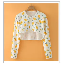 Detail of short cotton shoulder wrap featuring yellow lemon print and button closure