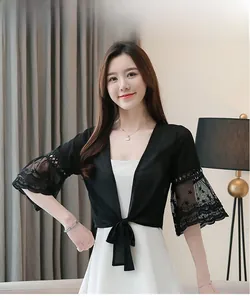 Détail d'un châle d'été noir en mousseline avec dentelle florale et manches évasées chic