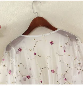 Detail of white mesh sun protection cardigan with purple floral embroidery on hanger