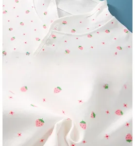 Close-up of cotton baby shawl collar with pink strawberry print and clear buttons
