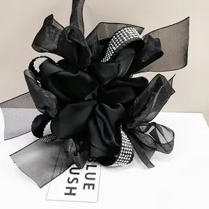 Detail of a black layered bow hair scrunchie with satin organza and white rhinestones