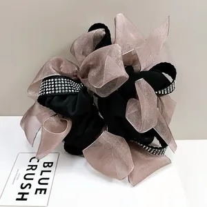 Macro detail of layered black organza bow scrunchie with sparkling rhinestone embellishments