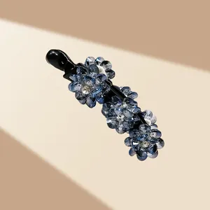 Détail de trois fleurs en cristal bleu sur une pince banane noire élégante pour femme