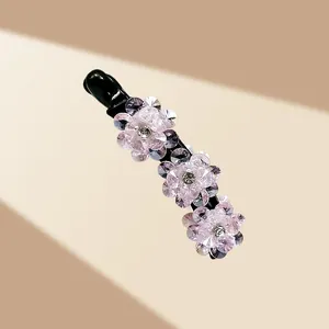 Détail macro de la pince banane haut de gamme avec trois fleurs en cristal rose et strass