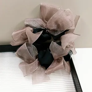 Close-up of champagne chiffon oversized bow scrunchie with sparkling rhinestone details