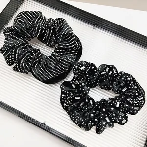 Detail view of two black fabric scrunchies with elegant rhinestone and crystal accents