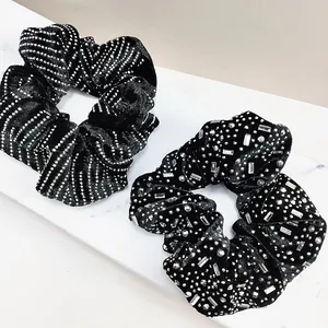 Close-up of black velvet scrunchies with silver rhinestones and metallic stud details