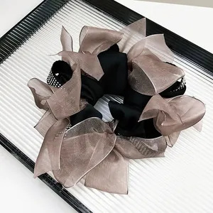 Detail of champagne organza hair scrunchie with sparkling rhinestones and black satin base