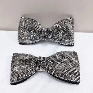 Elegant sparkling rhinestone bow hair clips in silver and black on a stone background