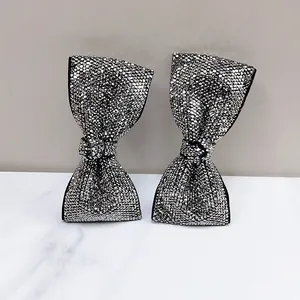 Close-up of elegant bow hair clips with silver rhinestones on a marble surface