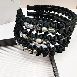 Detail van zwarte geplooide haarbanden met elegante parels, strass en bloemaccenten