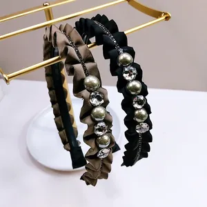 Detail van elegante geplooide satijnen haarbanden met parels en kristallen op gouden houder