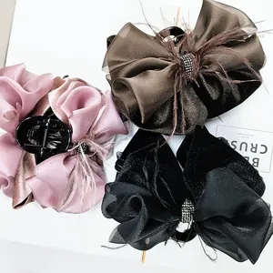 Three elegant fabric bow hair claws in pink, brown, and black with rhinestones and feathers