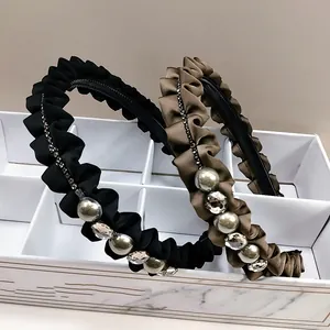 Detail van geplooide satijnen haarbanden met kristallen en parels op marmeren doos