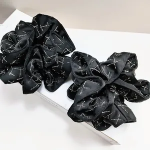 Close-up of black satin oversized scrunchies with shiny rhinestone cross patterns