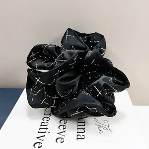 Macro detail of black satin scrunchie with sparkling diamond patterns on art book