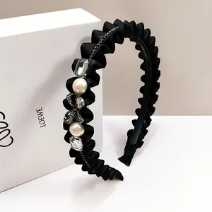Macro-opname van geplooide stoffen haarband met kristallen strass en parel accent