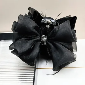 Detail of black bow hair claw with organza layers, feathers and rhinestone accents