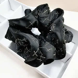 Black satin scrunchie with sparkling X-pattern rhinestones in a white storage box
