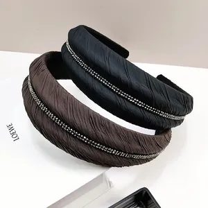 Détail de serre-têtes en tissu plissé noir et café avec bordure en strass étincelants
