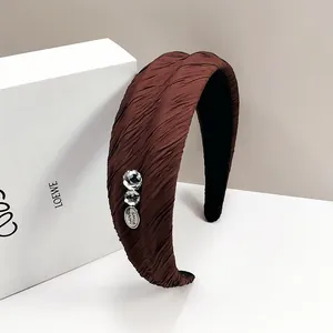 Dettaglio di cerchietto plissettato marrone scuro con ciondolo Smile Happy e strass