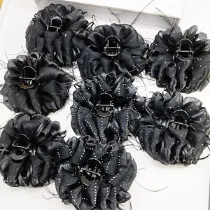 Detail of black cloud-textured chiffon flower hair claws with feathers and polka dots
