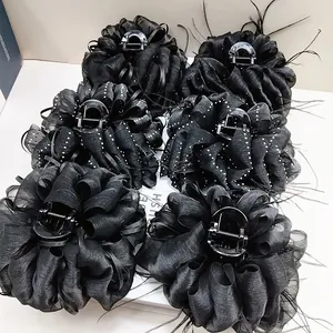 Detail view of large black cloud bubble yarn claw clips with elegant feather decorations