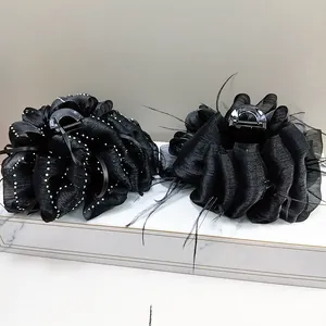 Detail view of large black cloud feather hair clips with pearls on marble display