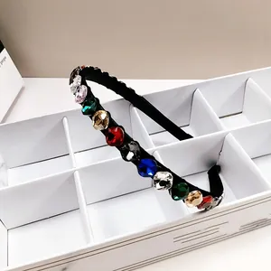 Detail van zwarte hoofdband met meerkleurige K9-kristallen in een witte opbergdoos