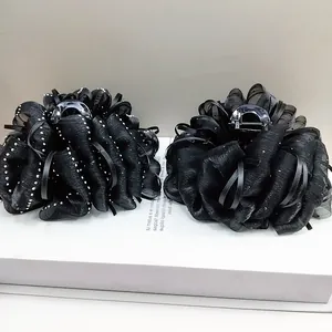 Detail of black cloud organza flower hair claw clip with sequin accents and ribbon