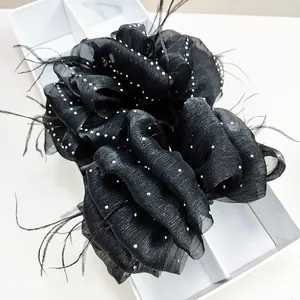 Detail of black cloud tulle hair claw clip with delicate feathers and sparkling sequins