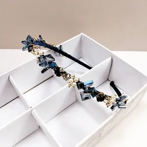 Détail de serre-tête luxe avec cristaux bleu foncé et perles blanches sur base noire