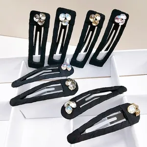 Detail of 8 black fabric snap clips with sparkling rhinestone floral accents on white stand