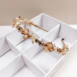 Détail d'un serre-tête de luxe avec cristaux champagne et perles blanches sur monture dorée