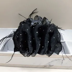 Detail of a large black cloud hair claw clip with seersucker fabric and feathers