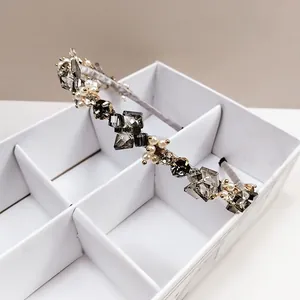 Gros plan d'un serre-tête en cristal gris et perles sur une boîte à bijoux