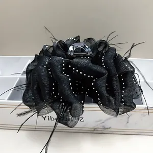 Close-up of large black puff gauze flower hair claw clip with feathers and rhinestones