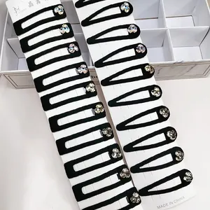 Detail of black BB hair clips with sparkling rhinestones on white marble background