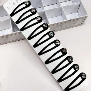 Set of 10 black snap hair clips with sparkling rhinestones on elegant marble background