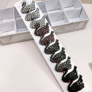 Detailed view of ten sparkling rhinestone swan hair clips in gradient colors on a white card