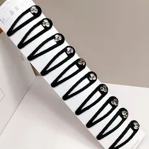 Close-up of ten black teardrop hair clips with sparkling rhinestone details on card